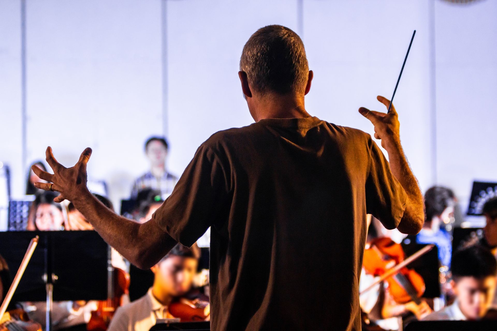 Back view of a male conductor directing his band at a local school concert